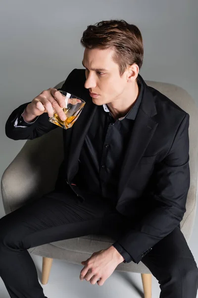 High angle view of pensive man drinking whiskey and looking away on grey background — Stock Photo