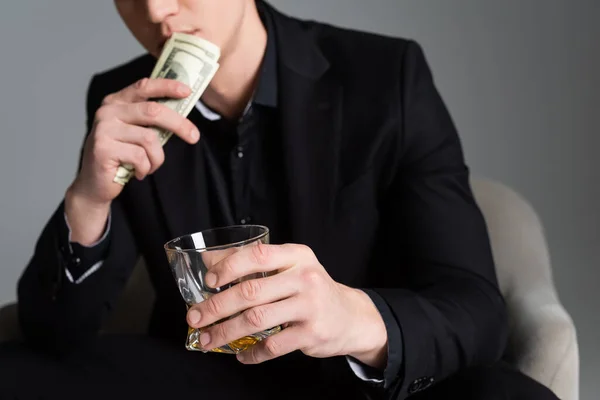 Ausgeschnittene Ansicht eines verschwommenen Mannes mit Dollars und Glas Whiskey isoliert auf grau — Stockfoto