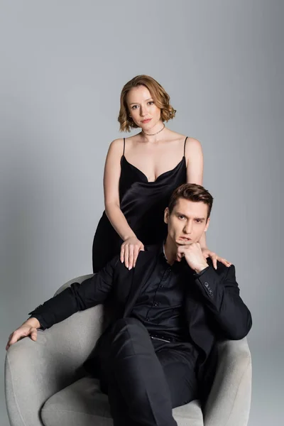Sexy couple in black clothes looking at camera isolated on grey - foto de stock