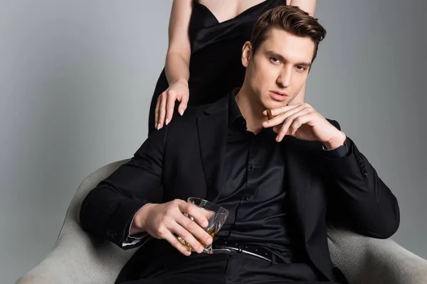 Man with whiskey and cigar looking at camera near woman isolated on grey - foto de stock