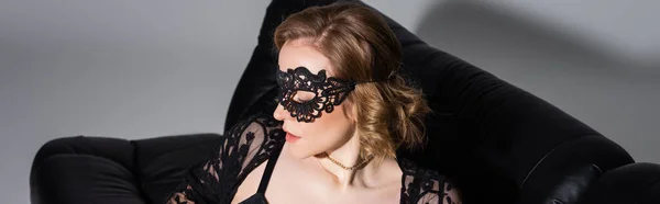 Sensual woman with wavy hair wearing black lace mask on grey background, banner — Fotografia de Stock