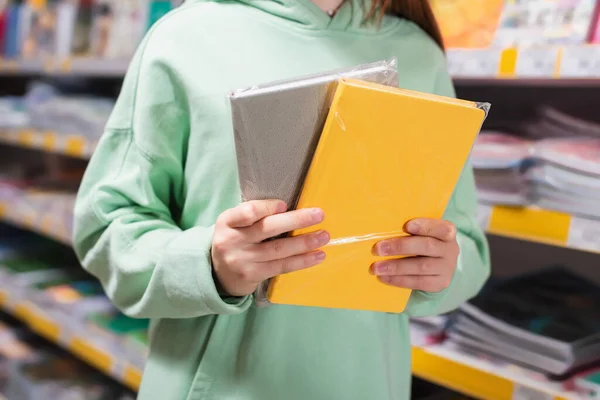 Partial view of child with colorful notepads in stationery store - foto de stock