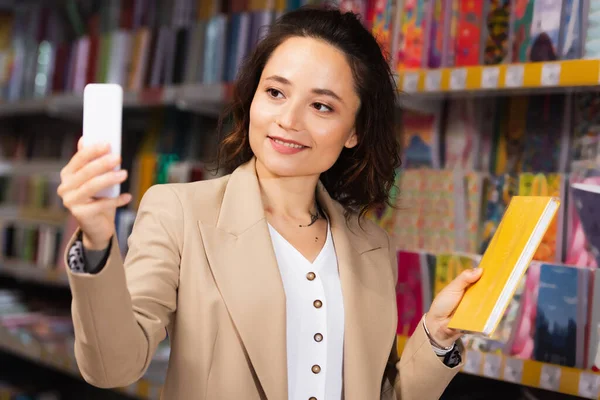Smiling woman taking photo with notebook in stationery shop — Stock Photo