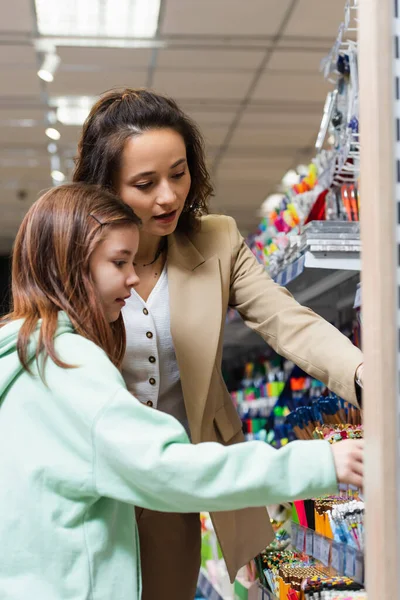 Mother and daughter near rack with different school supplies in stationery shop — Stock Photo