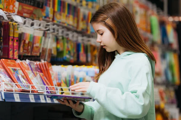 Side view of girl holding pencil set near rack in stationery shop — Foto stock