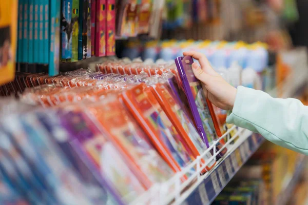 Cropped view of girl taking pencil set from blurred rack in stationery shop — Photo de stock