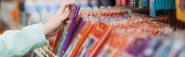 Cropped view of girl taking new pencil set from rack in stationery store, banner - foto de stock
