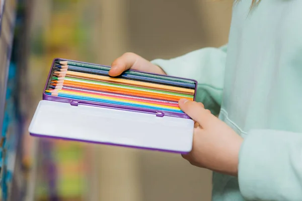 Partial view of child holding set of new color pencils - foto de stock