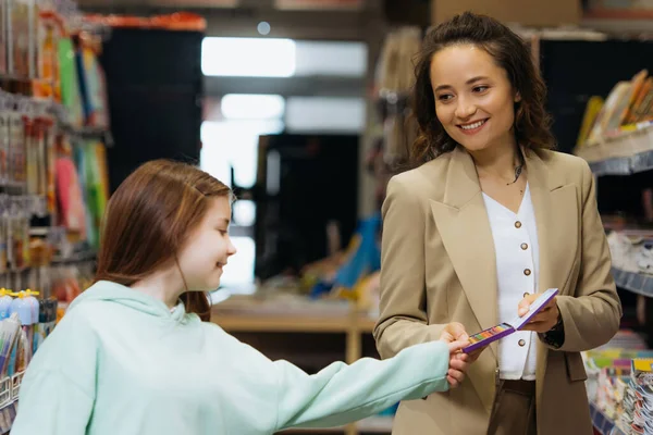 Pleased woman showing set of color pencils to daughter in stationery store — Stock Photo