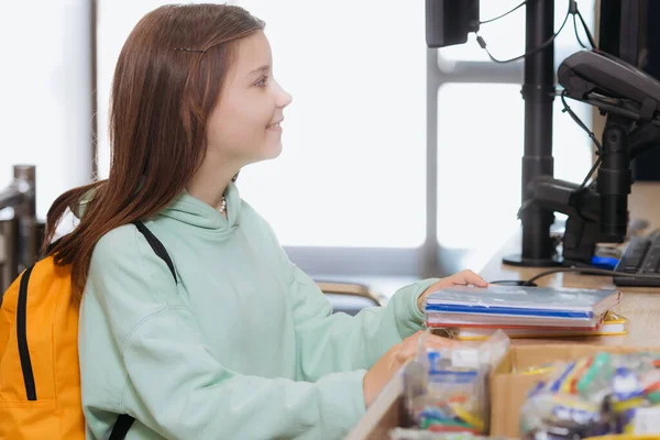 Side view of girl with new copybooks at cash desk in stationery store — Photo de stock