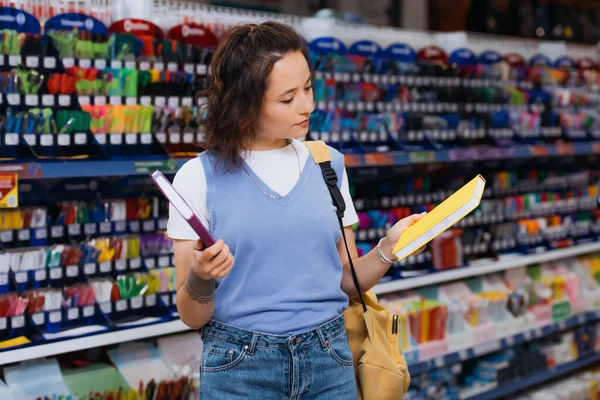 Junge brünette Frau wählt Notizblöcke im Schreibwarengeschäft — Stockfoto
