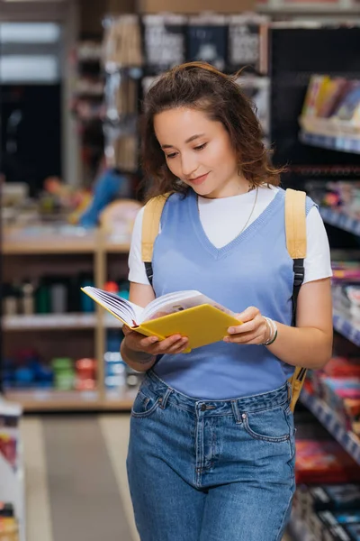 Young student looking at new notebook in blurred stationery store — стоковое фото