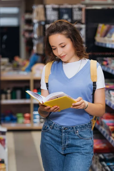 Young student looking at new notebook in blurred stationery store — Fotografia de Stock