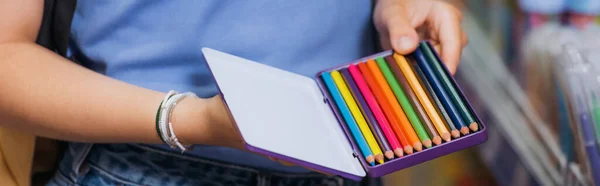 Cropped view of woman in beaded bracelets holding box of color pencils, banner - foto de stock