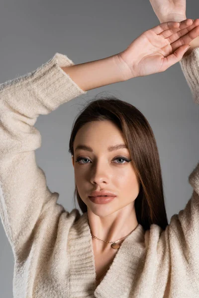 Charming woman with makeup standing with arms up and looking at camera isolated on grey — Foto stock