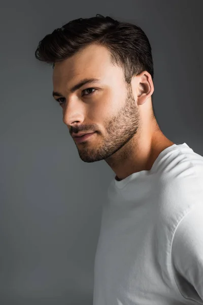 Portrait of brunette man in white t-shirt looking away isolated on grey — Photo de stock