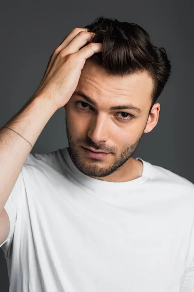 Портрет брюнетки в футболці торкаючись волосся ізольовані на сірому — стокове фото