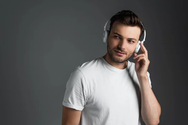 Young man listening music in headphones isolated on grey — Stock Photo