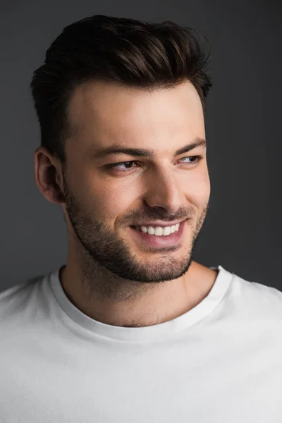 Portrait of bearded and smiling man in white t-shirt looking away isolated on grey — Photo de stock