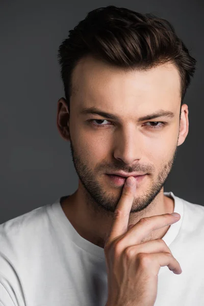 Portrait of brunette man showing secret gesture isolated on grey — Photo de stock