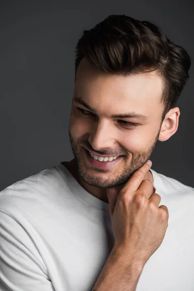 Happy man touching neck and looking away isolated on grey — Photo de stock