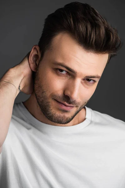 Portrait of brunette man in white t-shirt looking at camera isolated on grey — Stockfoto