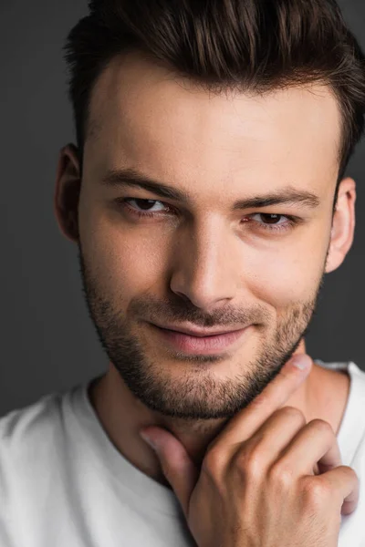 Portrait of smiling and bearded man touching neck isolated on grey — Foto stock