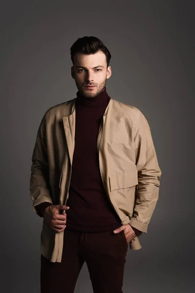 Stylish brunette man in jacket posing isolated on grey — Stock Photo