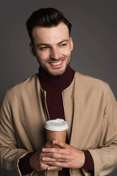 Portrait of positive man in autumn jacket holding takeaway drink isolated on grey — Photo de stock