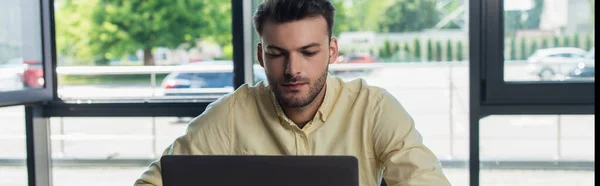 Молодий бізнесмен використовує ноутбук під час роботи в офісі, банер — стокове фото