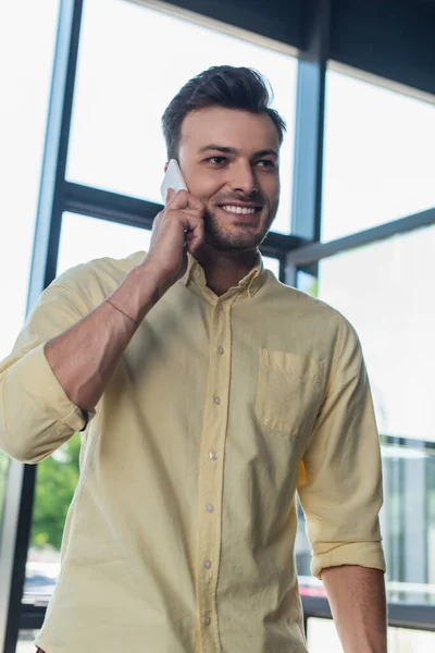 Positive businessman in shirt talking on smartphone in office — Stockfoto