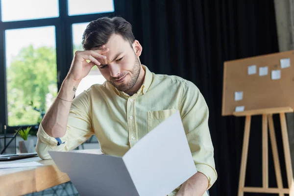 Focused businessman looking at blurred paper folder in office — Stock Photo