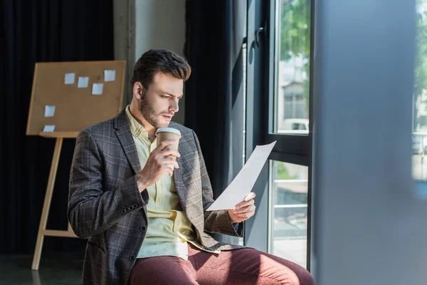 Businessman in jacket holding document and coffee to go in office — Stock Photo