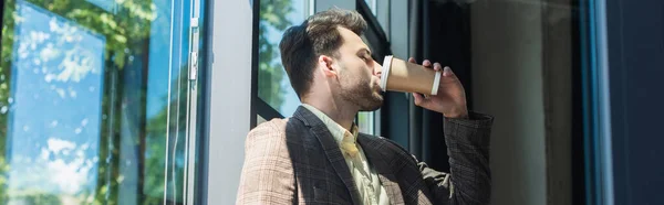 Side view of businessman in jacket drinking coffee to go in office, banner — Stockfoto