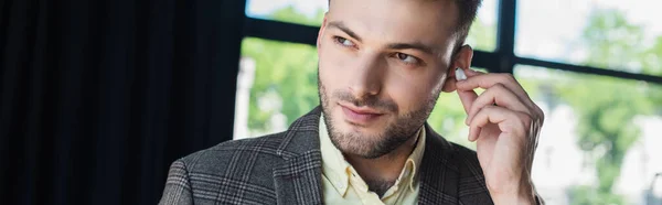 Young businessman in jacket holding earphone in office, banner — Stock Photo