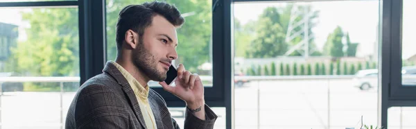 Side view of businessman talking on smartphone in office, banner — Photo de stock