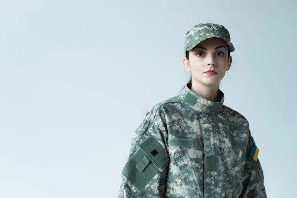 Soldier with ukrainian flag on military uniform looking at camera isolated on grey — Stock Photo