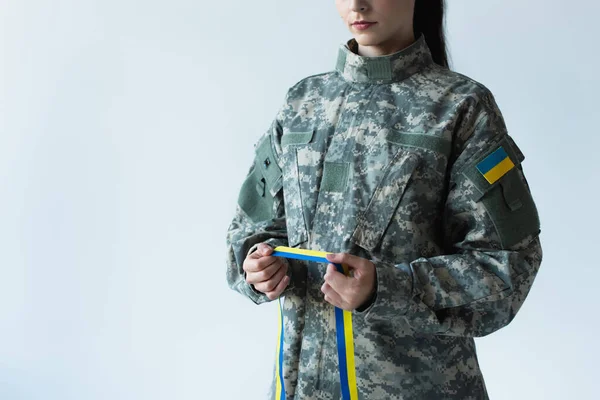 Cropped view of soldier in uniform holding blue and yellow ribbon isolated on grey — Fotografia de Stock