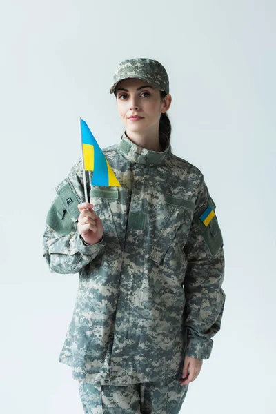 Young soldier holding ukrainian flag and looking at camera isolated on grey — Photo de stock