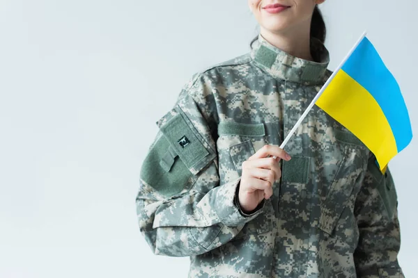 Cropped view of smiling servicewoman holding ukrainian flag isolated on grey — Fotografia de Stock