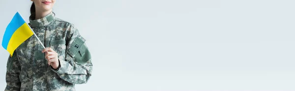 Розбитий погляд на позитивного солдата, який тримає прапор україніана ізольований на сірому прапорі. — стокове фото