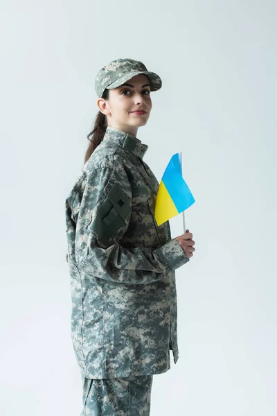 Young servicewoman holding ukrainian flag isolated on grey — Stock Photo