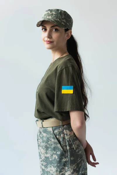 Young soldier with ukrainian flag on chevron looking at camera isolated on grey - foto de stock