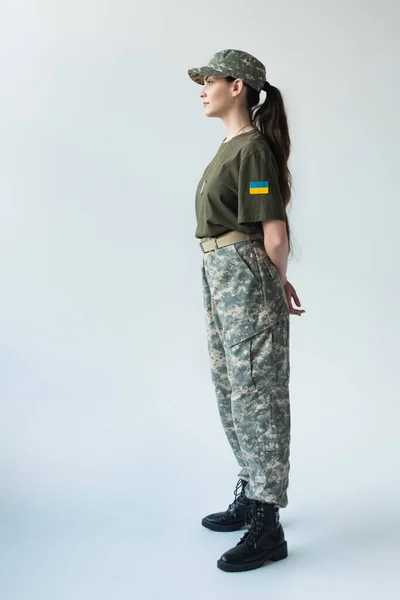 Side view of soldier with ukrainian flag on chevron looking away on grey background — стокове фото