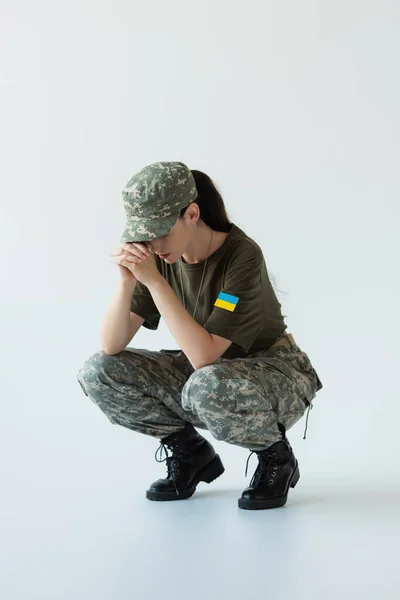 Disappointed soldier with ukrainian flag on chevron on grey background — стоковое фото