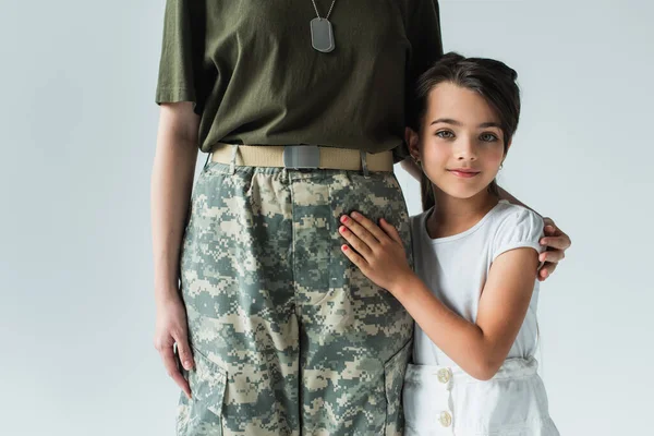 Soldier in uniform hugging smiling daughter isolated on grey — Stockfoto