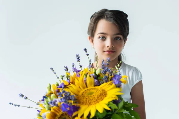 Child holding blue and yellow flowers isolated on grey — Foto stock