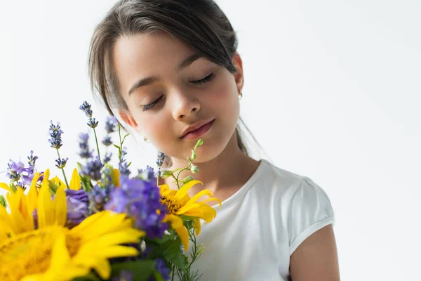 Portrait of kid closing eyes near blue and yellow flowers isolated on grey — Photo de stock