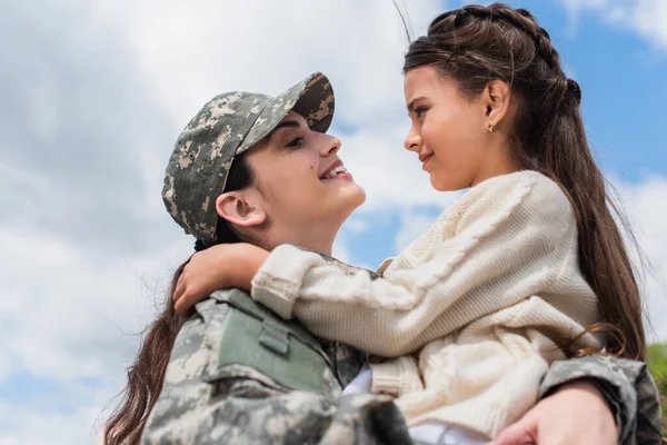 Side view of woman in military uniform embracing daughter outdoors — Stock Photo