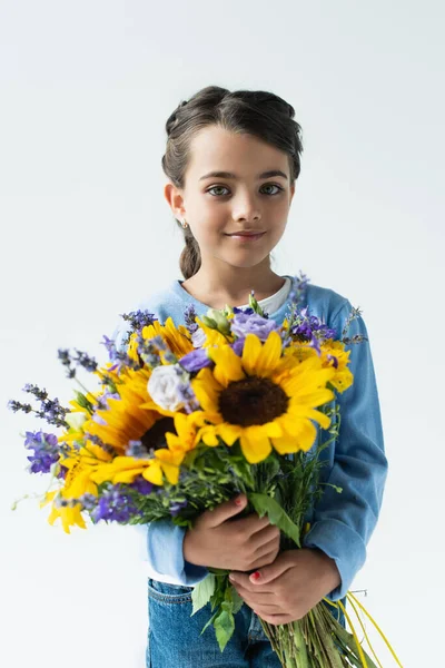Патріотична дівчина з синьо-жовтим букетом посміхається на камеру ізольовано на сірому — стокове фото